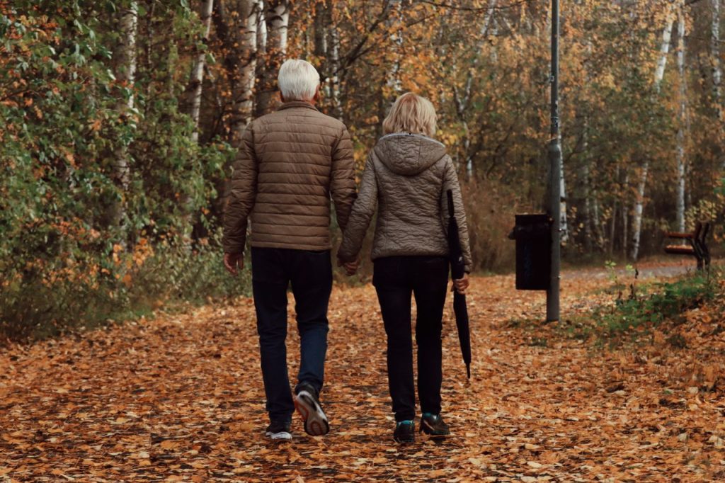 Senior couple enjoying a peaceful walk through a leafy park in Jönköping, Sweden during autumn.