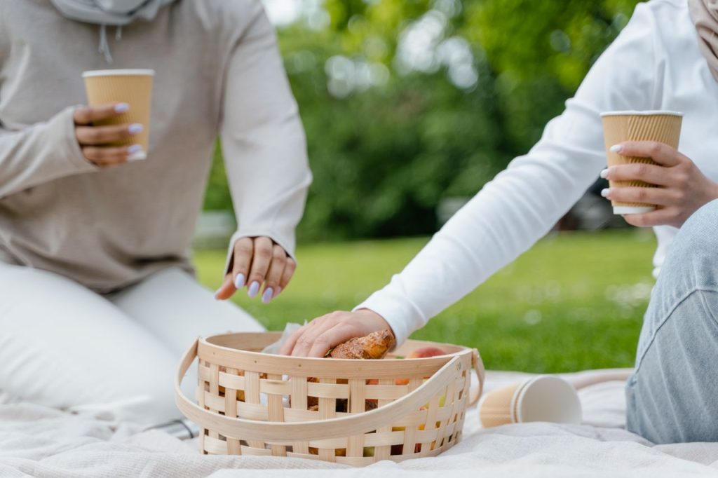 Relaxing picnic scene with a basket and coffee cups outdoors on a sunny day.